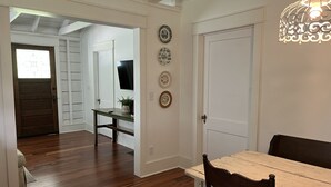 Un comedor con una mesa y sillas de madera, un televisor montado en la pared y platos decorativos.