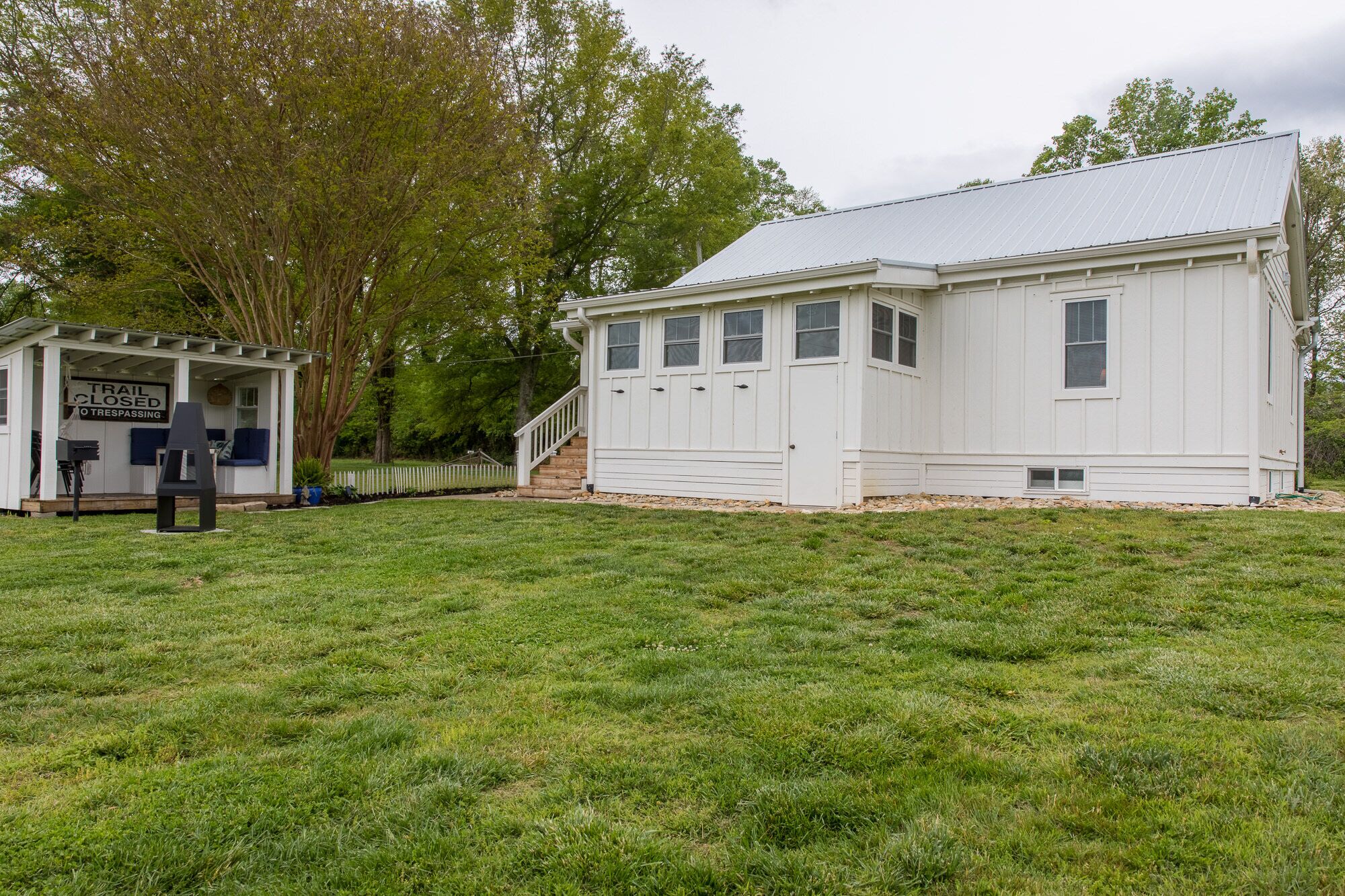 A white building with a covered porch and a staircase leading to a door.
