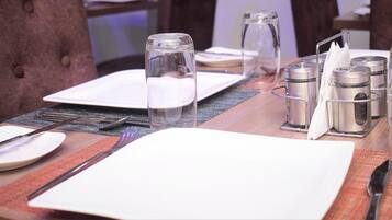 A neatly set dining table with plates, cutlery, glasses, and condiment containers.