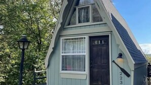 A small, single-story house with a steeply pitched roof, a front door, and a window. - Tiny AFrame/Fire Pit/Pets/Lake Access/Dogwood Canyon (Lampe)