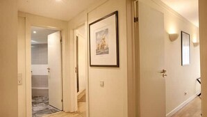 A hallway with doors, framed pictures, and a staircase leading to a bathroom.