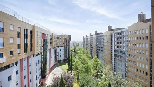 A high-rise residential building with multiple floors, balconies, and a central courtyard with trees.