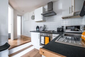 Enjoy cooking in this well-equipped kitchen with a black countertop, stainless steel appliances, and white cabinetry.