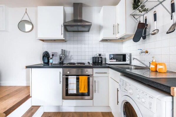 Kitchen features a stainless steel range hood, oven, microwave, and integrated washing machine.