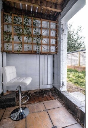 Relax in a serene space with a cushioned bench and a chair, surrounded by lush greenery.