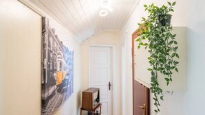 Un pasillo con una puerta, una mesita y una planta colgante.