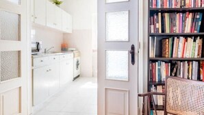 Una cocina moderna con armarios blancos, lavadora y una estantería llena de libros.