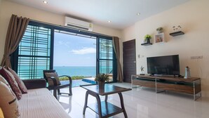 Una sala moderna con televisor grande, zona de estar y vista al mar.