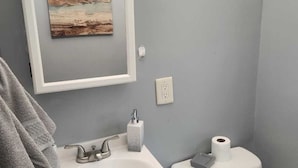 A bathroom with a white sink, a toilet, and a framed artwork on the wall. - Derby rental furnished 2BR, 1 full bath(shower/tub) house (Louisville)