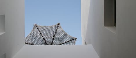 A modern architectural structure with a clear sky view, featuring a geometric roof and a minimalist design.