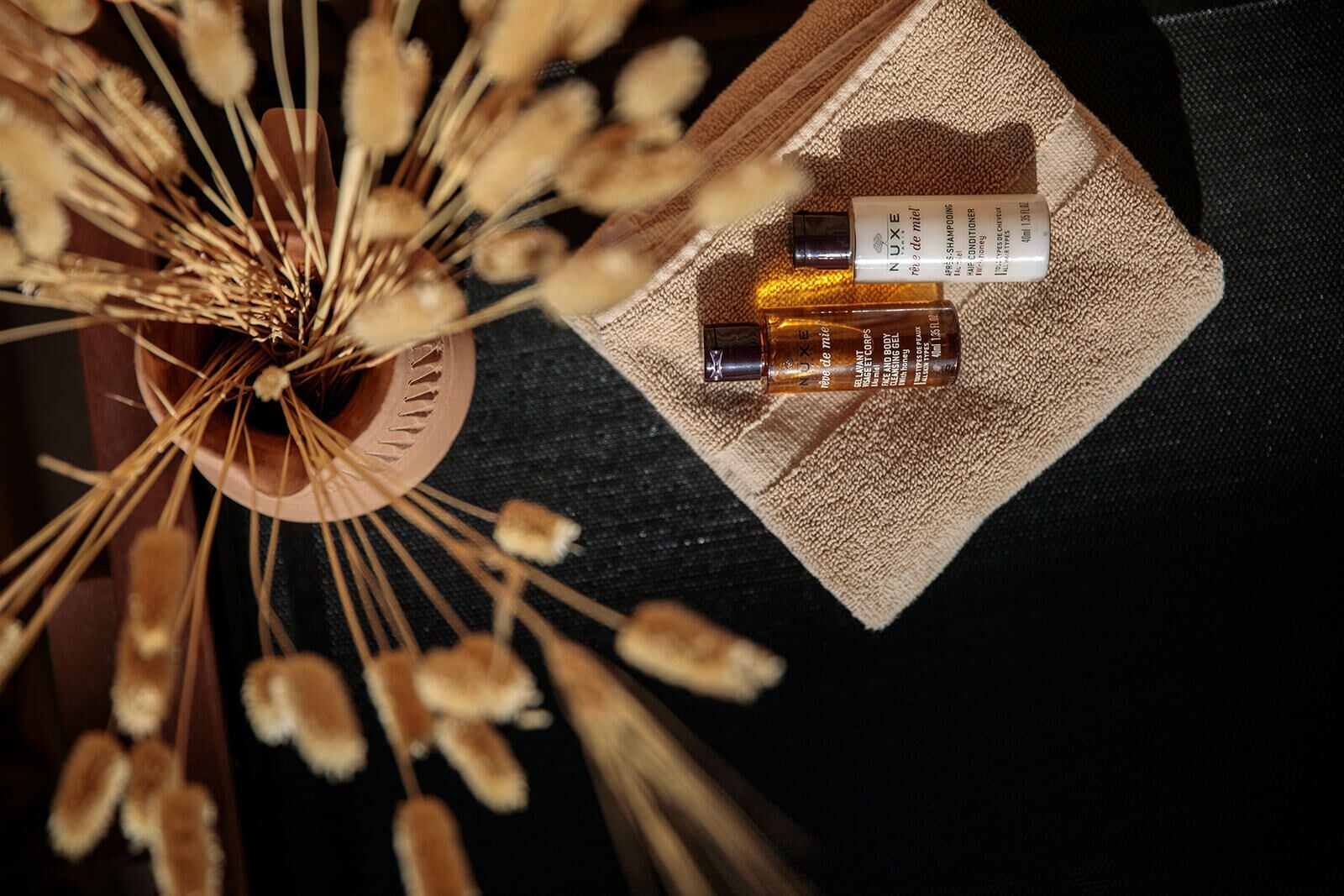 A top-down view of a bathroom with a wooden sink, a towel, and a bottle of shampoo.