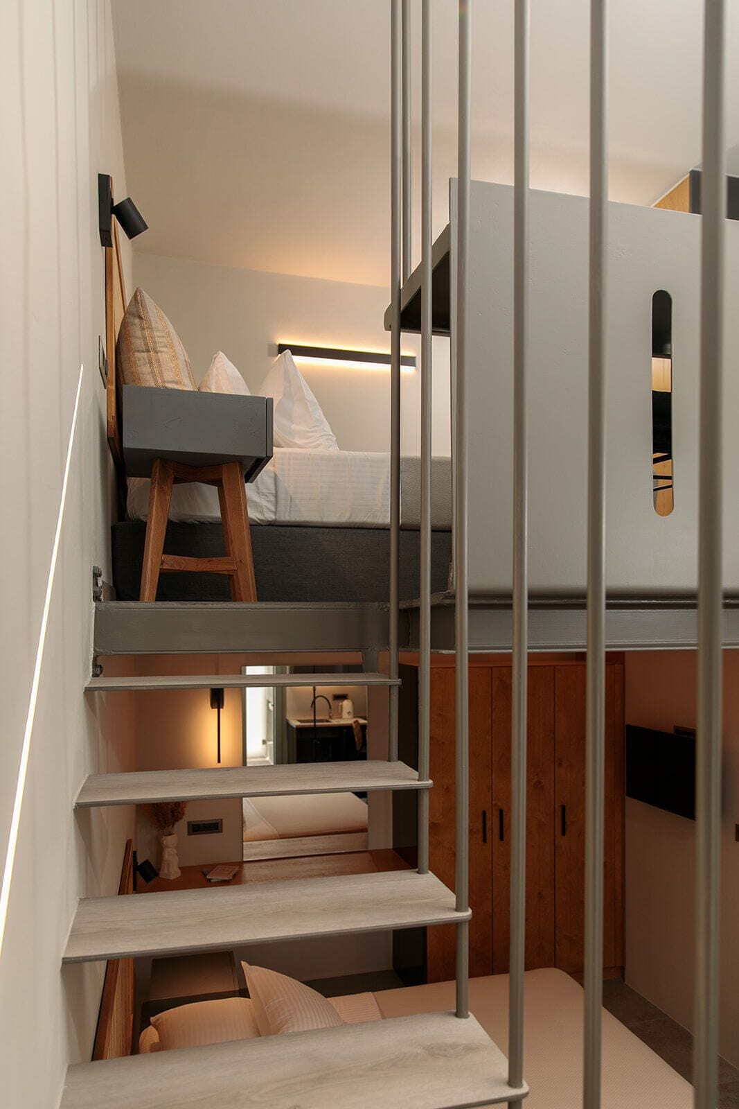 A compact, modern room with a bed, a desk, and a kitchenette.
