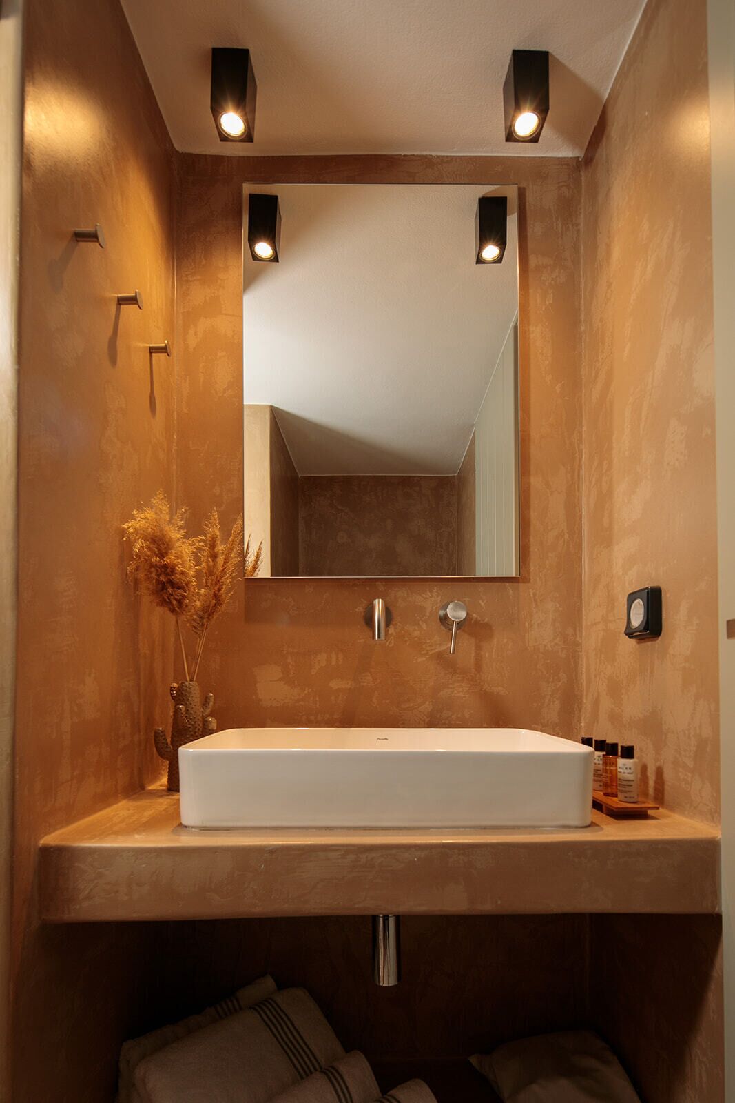 Une salle de bain moderne avec un grand lavabo rectangulaire, un miroir et un éclairage encastré.