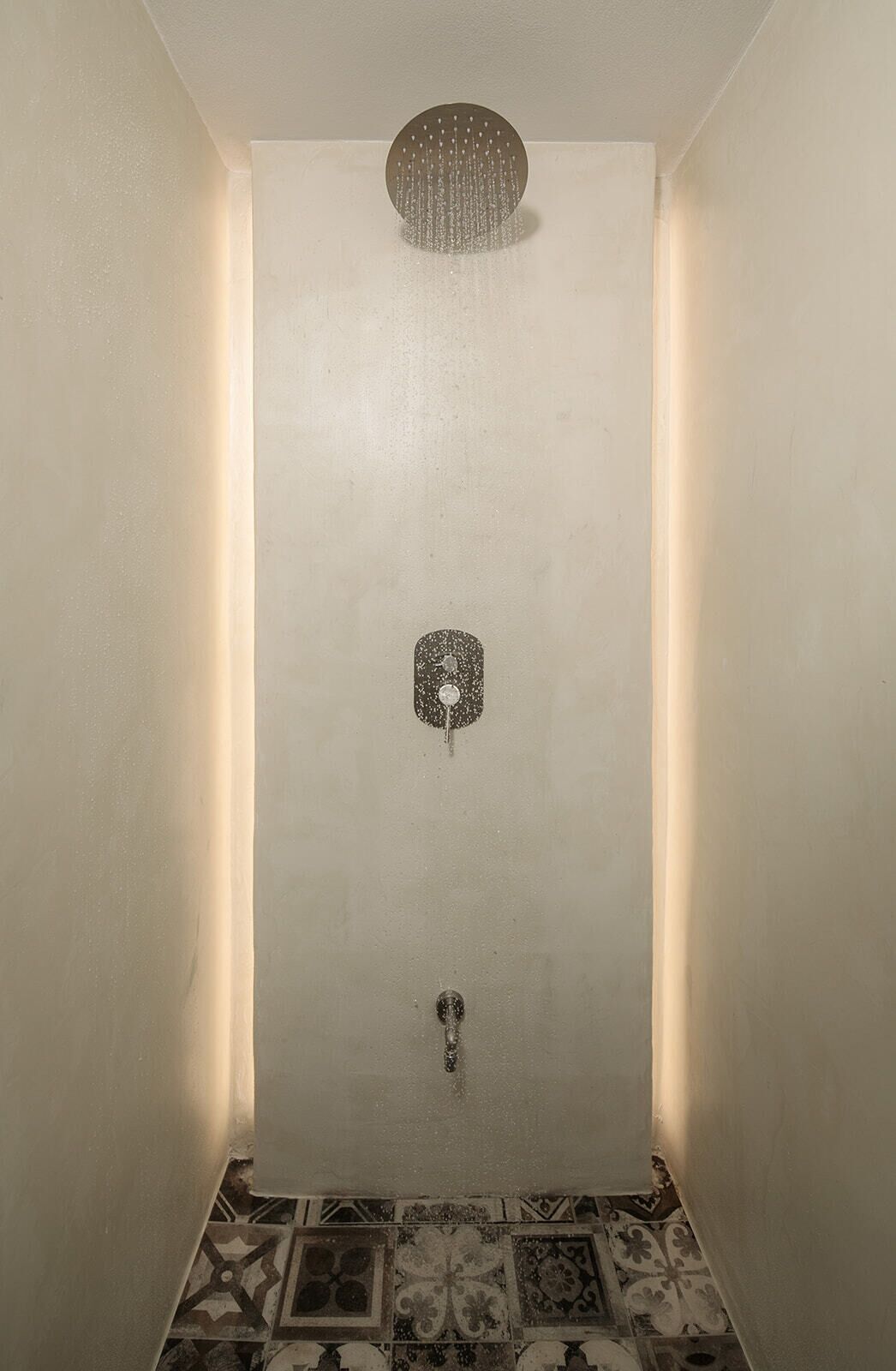 A shower with a circular head, a showerhead, and a control panel.