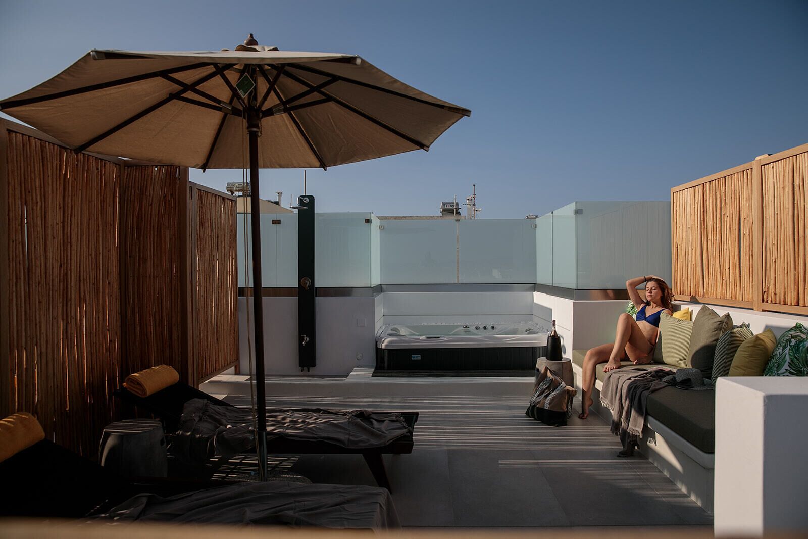 A rooftop terrace with a hot tub, a large umbrella, and a sofa.