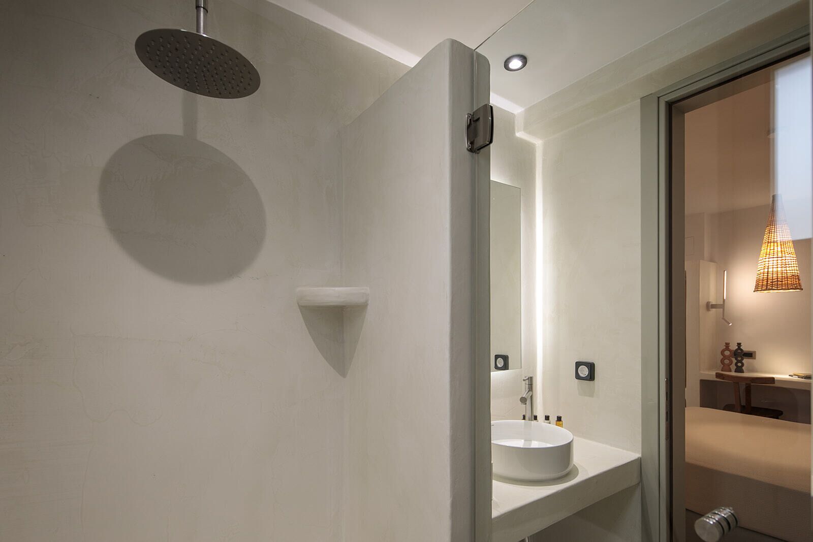 A modern bathroom with a round showerhead, a white sink, and a mirror.