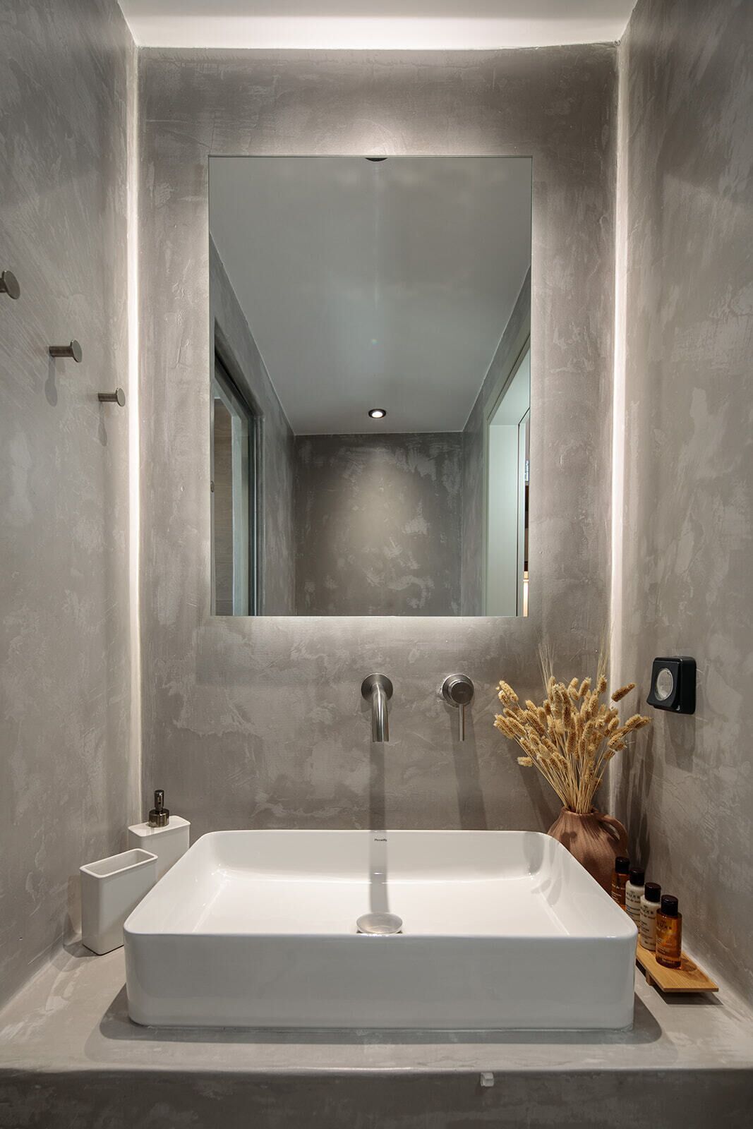 A modern bathroom with a rectangular sink, a large mirror, and a recessed ceiling light.
