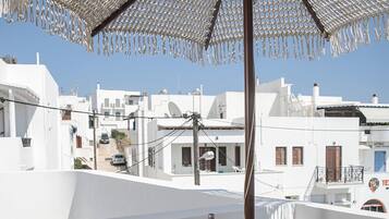 A terrace with a table set for two, a bottle of wine, and a plate of food.