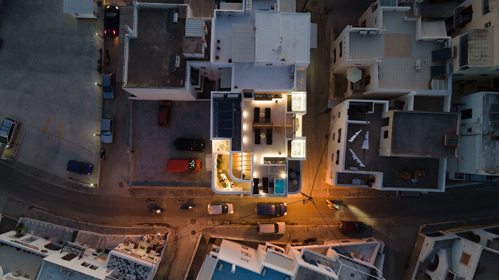 An aerial view of a multi-story building with a central courtyard, multiple balconies, and a parking area.