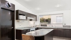 Une cuisine moderne avec des meubles de couleur sombre, un îlot central et une fenêtre offrant une vue dégagée.