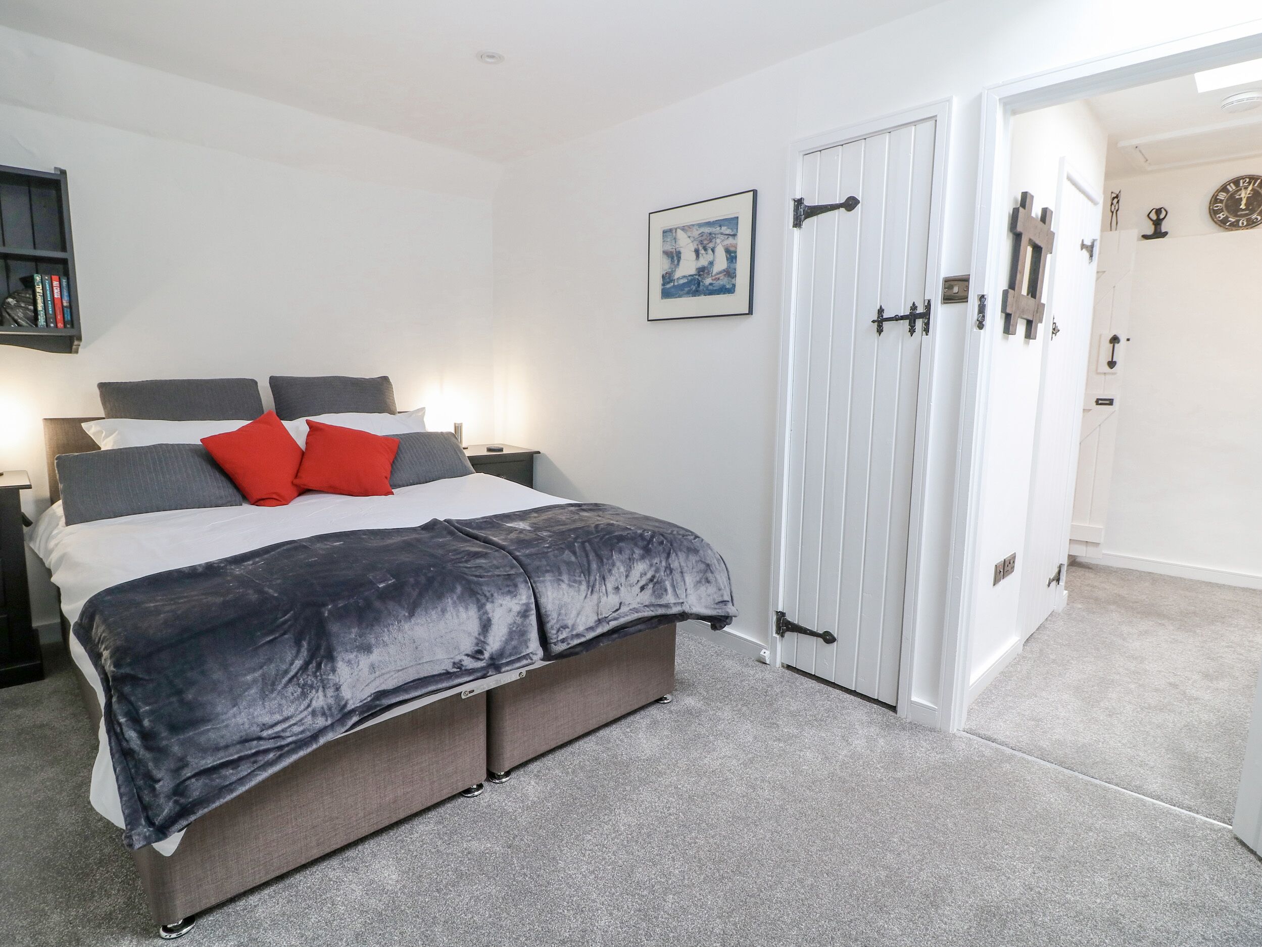 A bedroom with a bed, bedside tables, a wardrobe, and a painting on the wall.