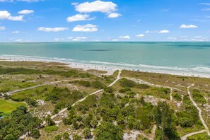 An aerial view of a beach with clear skies, a sandy shore, and a mix of greenery and paths. - Pet Friendly home, Close to Sarasota Beach! (Siesta Key)