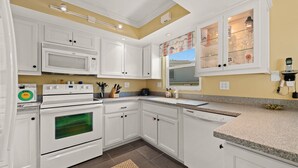 A modern kitchen with white cabinetry, a built-in microwave, and a large oven.