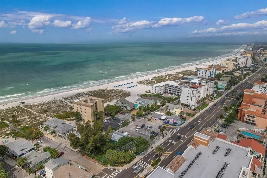 An aerial view of a coastal city with a beach, buildings, and roads.