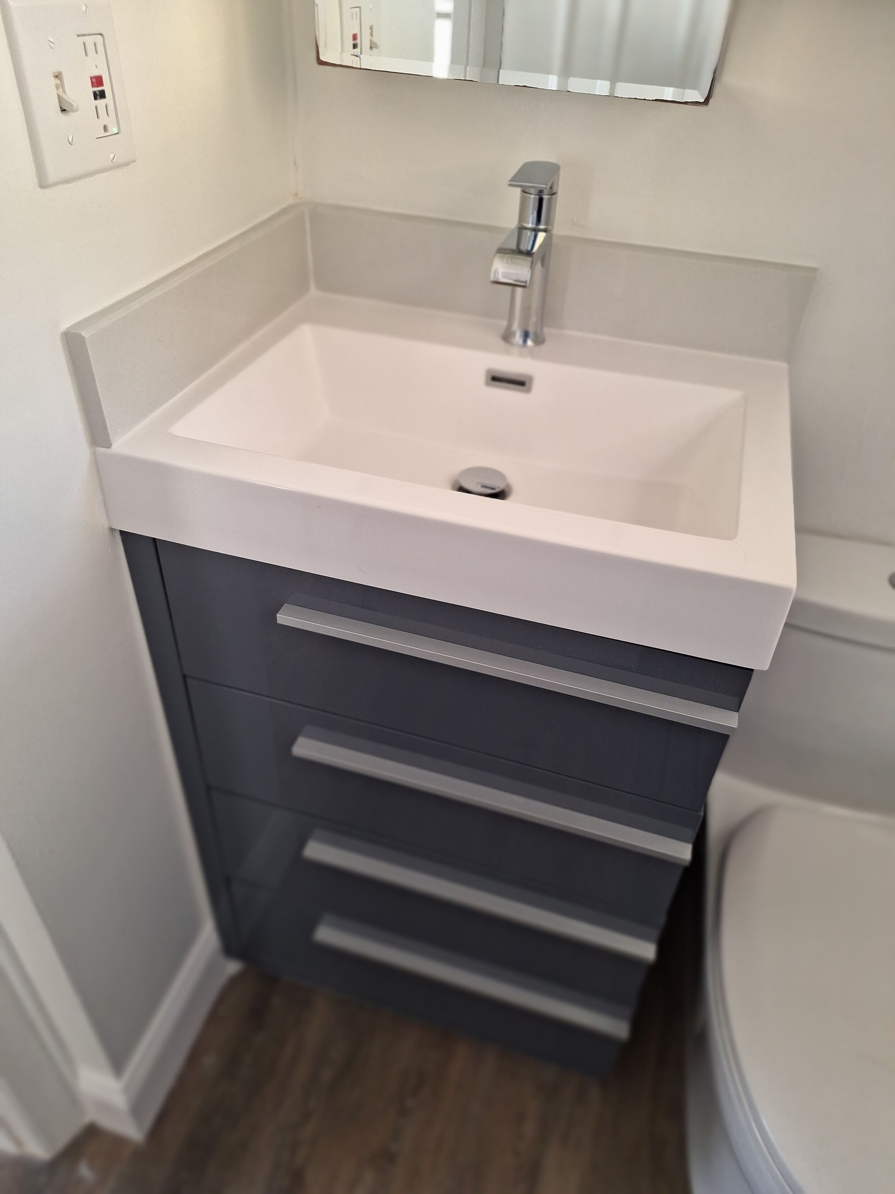 A bathroom with a white sink, a mirror above it, and a toilet to the right.