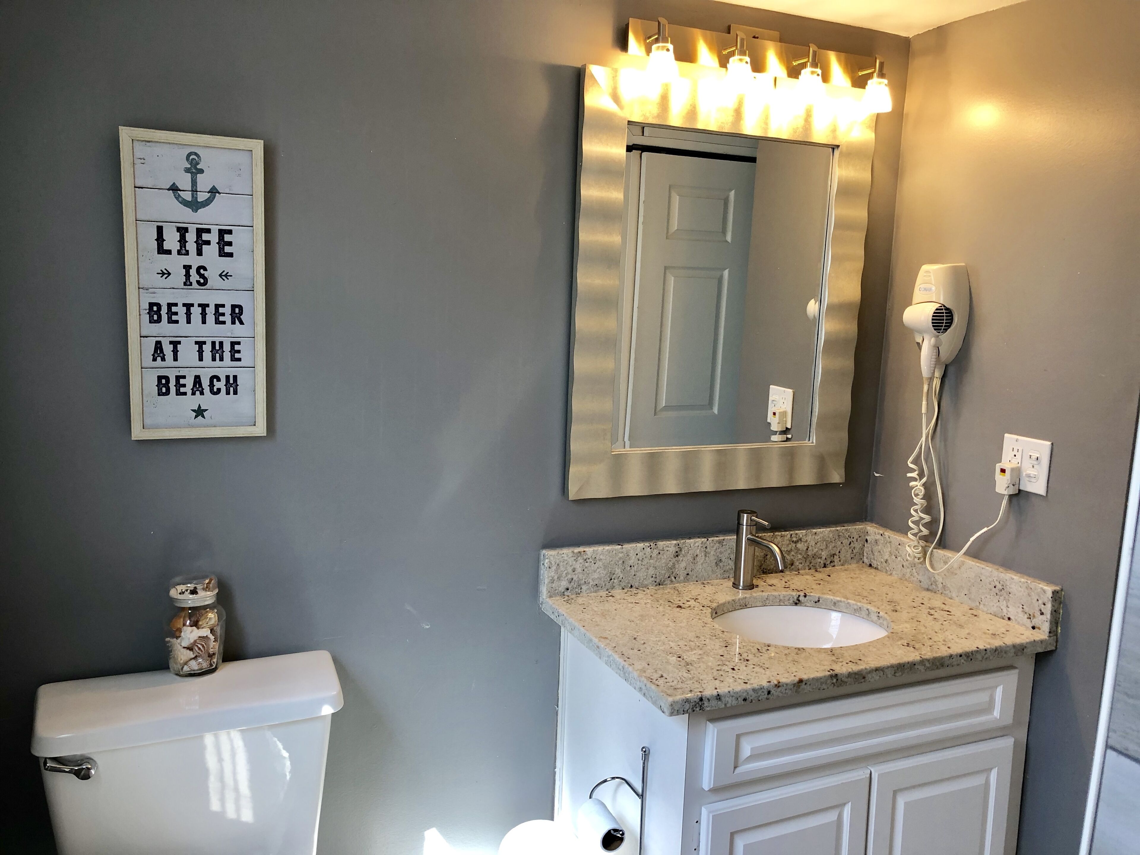 Een badkamer met toilet, wastafel, spiegel en een motiverende tekst op de muur.