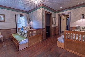 Quarto com duas camas de madeira, uma cômoda de madeira, janela com cortinas e um quadro emoldurado na parede.