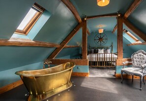 Relax in a spacious loft-style room with a bathtub and exposed beams.