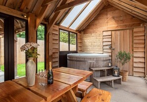 Relax in this cabin-style room with a high ceiling, skylight, and hot tub, perfect for social gatherings and unwinding.