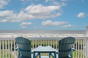 A deck with two chairs and a table overlooking a beach with umbrellas and people. - Top Floor Unit in Sea Colony w extraordinary views (Carolina Beach)