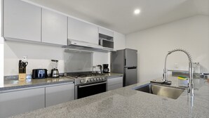 Una cocina moderna con armarios blancos, estufa de acero inoxidable, microondas y refrigerador.