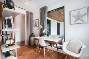 Une piĂšce moderne comprenant une table Ă manger, des chaises, un fauteuil blanc, une grande fenĂȘtre et une dĂ©coration murale reprĂ©sentant une Ă©toile de mer.