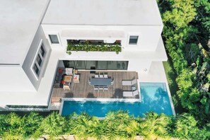 Ein modernes Haus mit Pool auf dem Dach, Essbereich und Balkon mit Grünpflanzen.