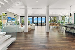 A spacious living area with a view of the ocean, wooden flooring, and modern furniture.