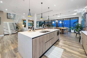 A modern kitchen with a central island, pendant lighting, and a view of the outdoors. - Luxury Bayfront Villa with Pool New Construction (North Bay Village)