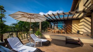 A sunlit patio with lounge chairs, a table, and an umbrella. - Hotel Barra da Lagoa by Latitud Hoteles (Búzios)