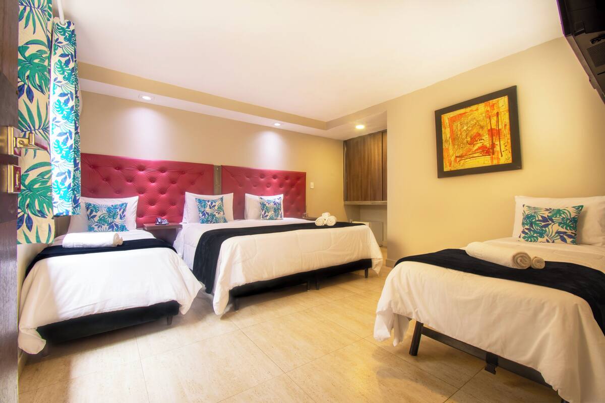 Une chambre d’hôtel avec deux lits, une tête de lit rouge et un tableau au mur.
