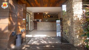 A hotel entrance with a wooden facade, a reception desk, and a stone pillar. - Hotel Barra da Lagoa by Latitud Hoteles (Búzios)