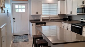 A modern kitchen with white cabinets, a large island, and a stainless steel sink.