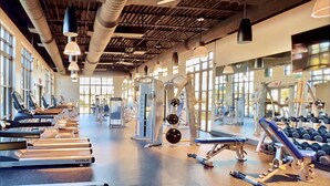 Ein Fitnessstudio mit Laufbändern, Kraftgeräten und Kurzhanteln.
