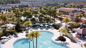 Ein Resort mit einem großen Pool, Palmen und mehreren Gebäuden.