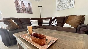 A wooden coffee table with a copper tray and candle.