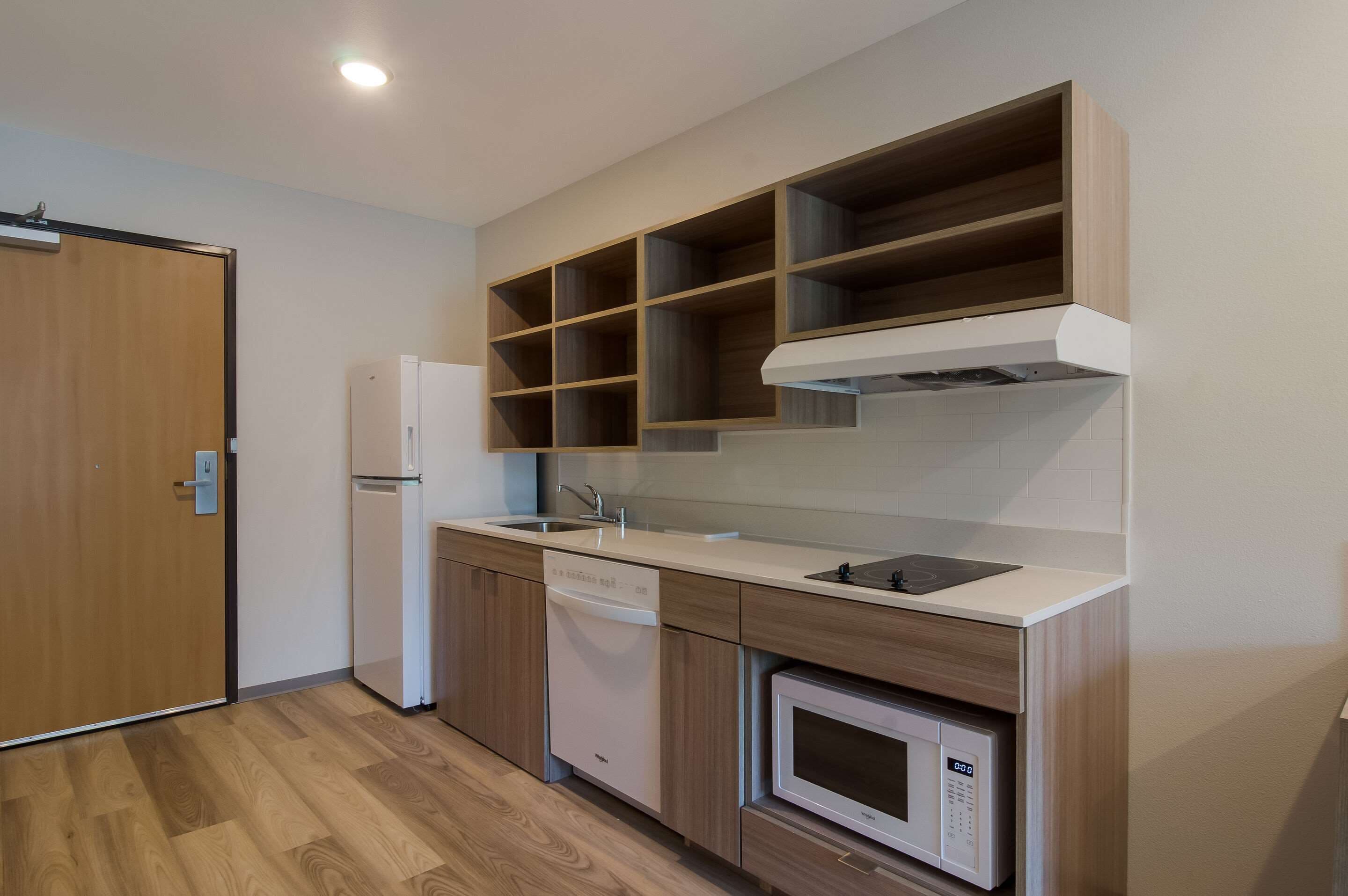 Una cocina moderna con armarios de madera, microondas integrado y lavavajillas.