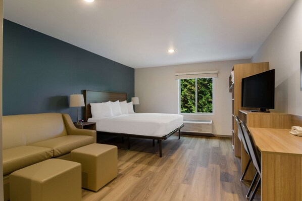 Una habitación de hotel moderna con cama, sofá, escritorio y televisor.