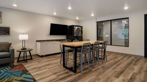 Una sala de estar moderna con comedor, un televisor de pantalla plana en la pared y un gran ventanal.
