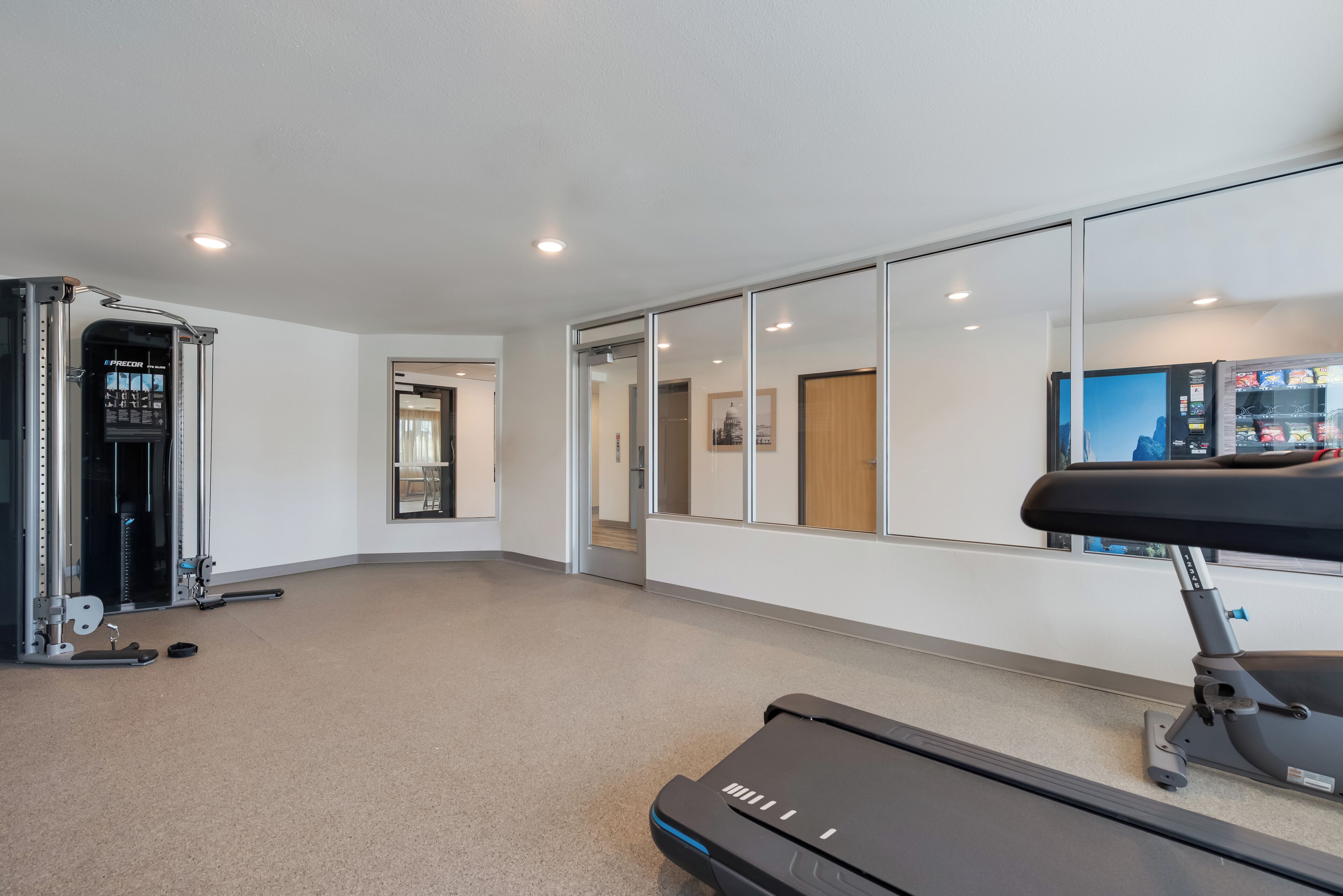 Ein modernes Fitnessstudio mit Laufband, Kraftgeräten und einer Spiegelwand.